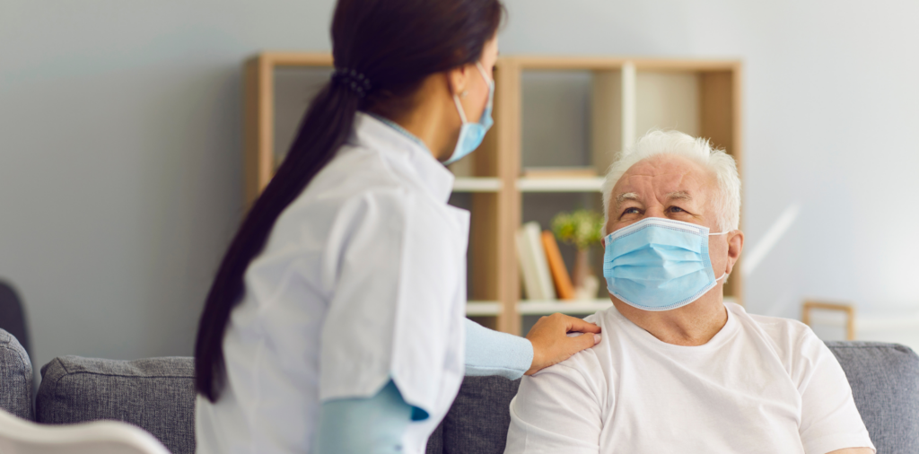 Un vieil homme portant un masque, et son aide soignante