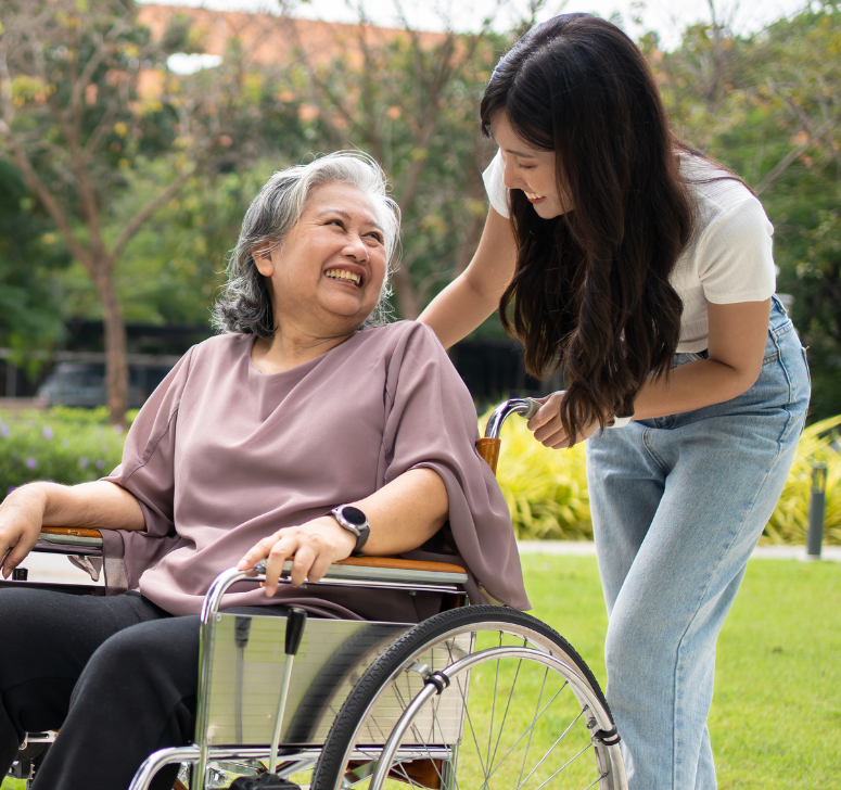 Une jeune femme pousse le fauteuil d'une une personne âgée