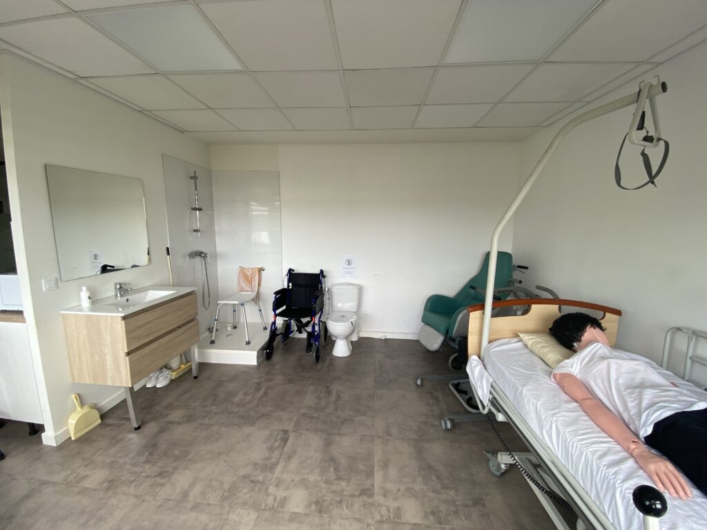 un appartement pédagogique comprenant une vasque et une douche, un lit médicalisé, un monte personne, un fauteuil roulant, un mannequin et bien d'autres accessoires d'aide aux personnes